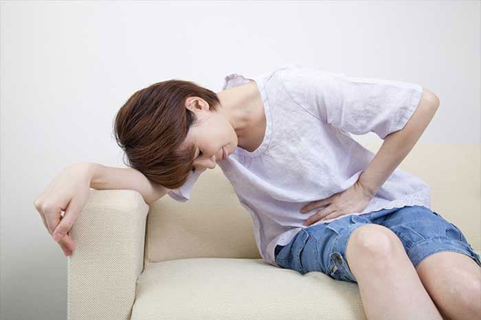 お腹を痛がる女性